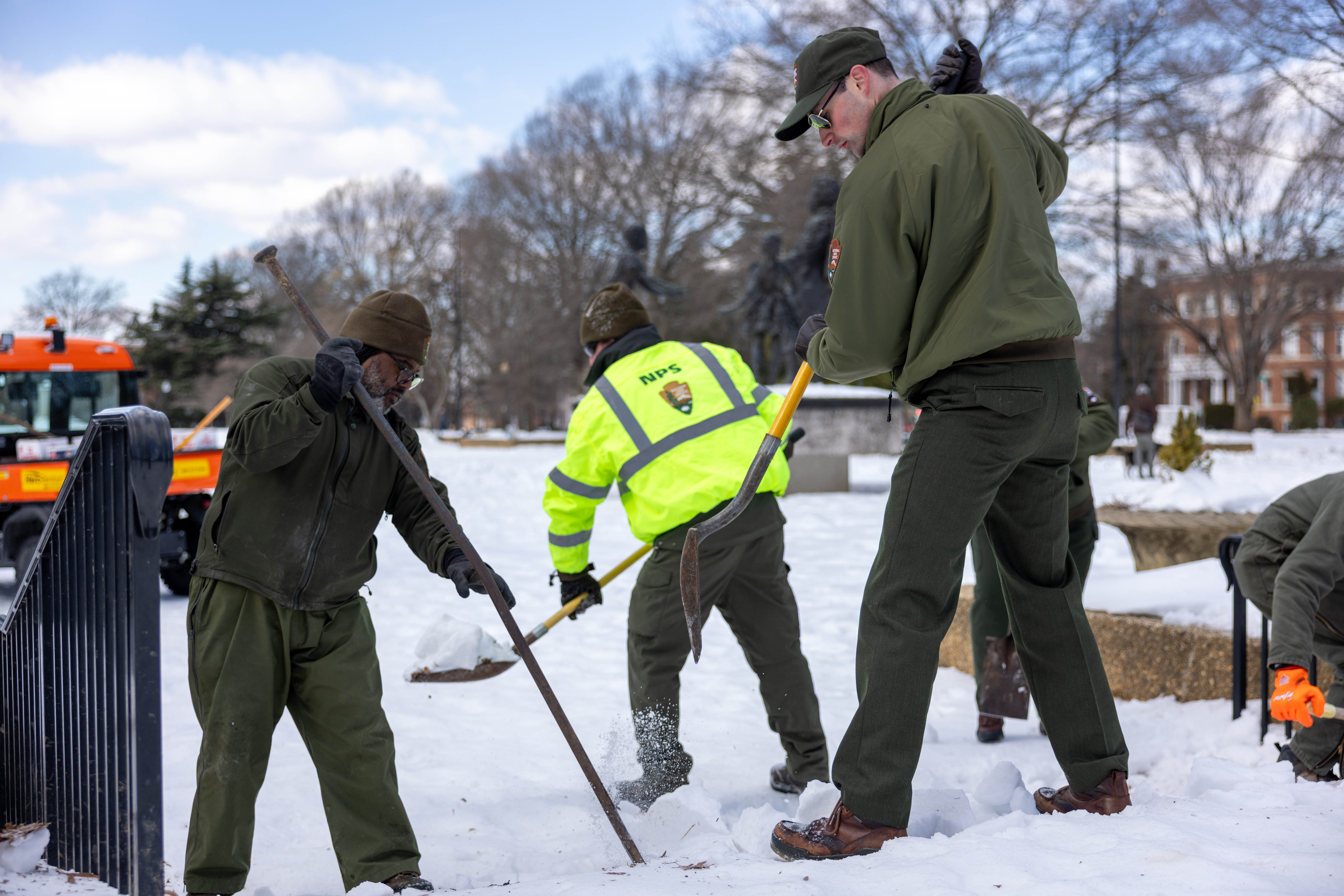Three National Park Service staff members shovel snow