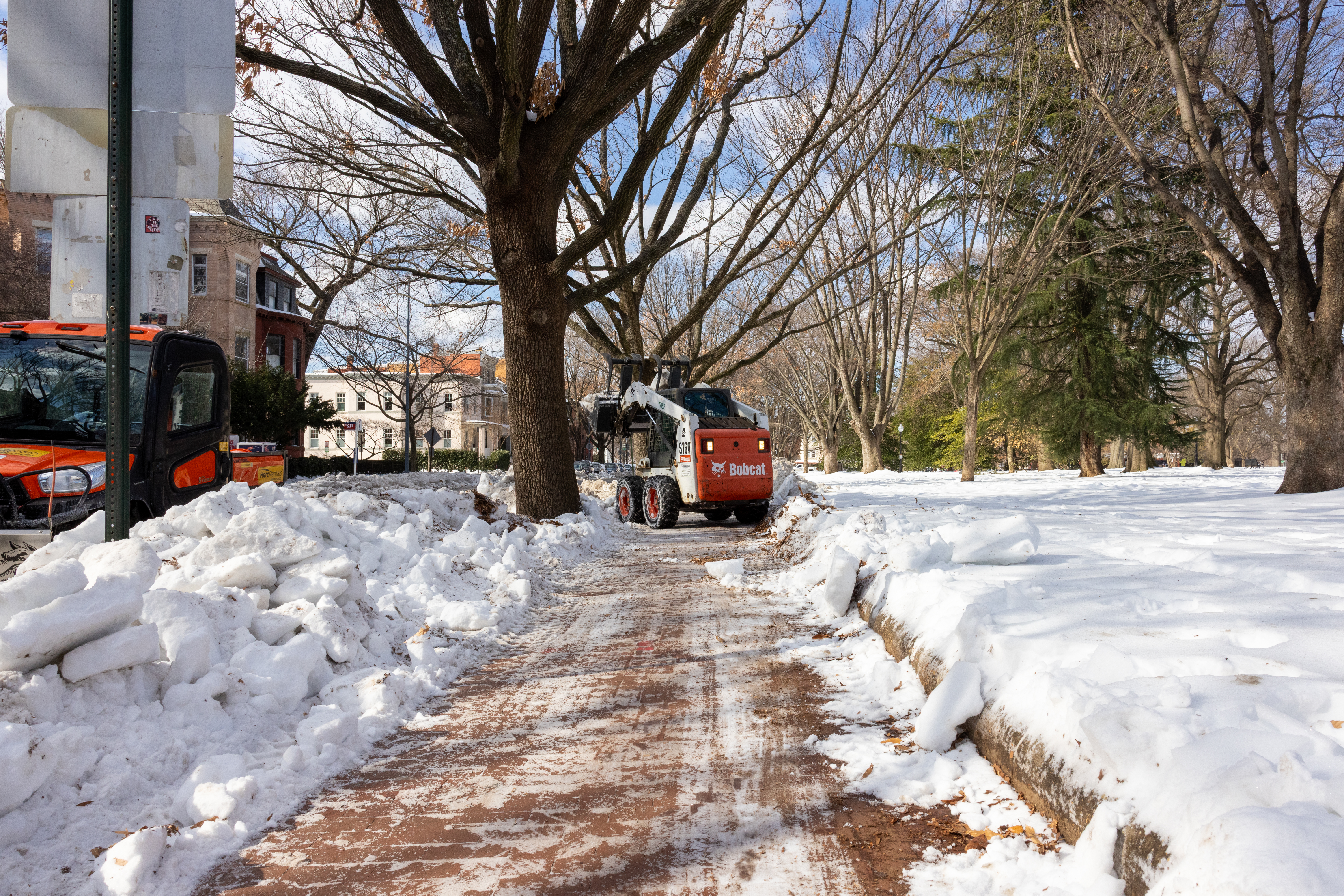 A utility vehicle clears snow from a sidewalk