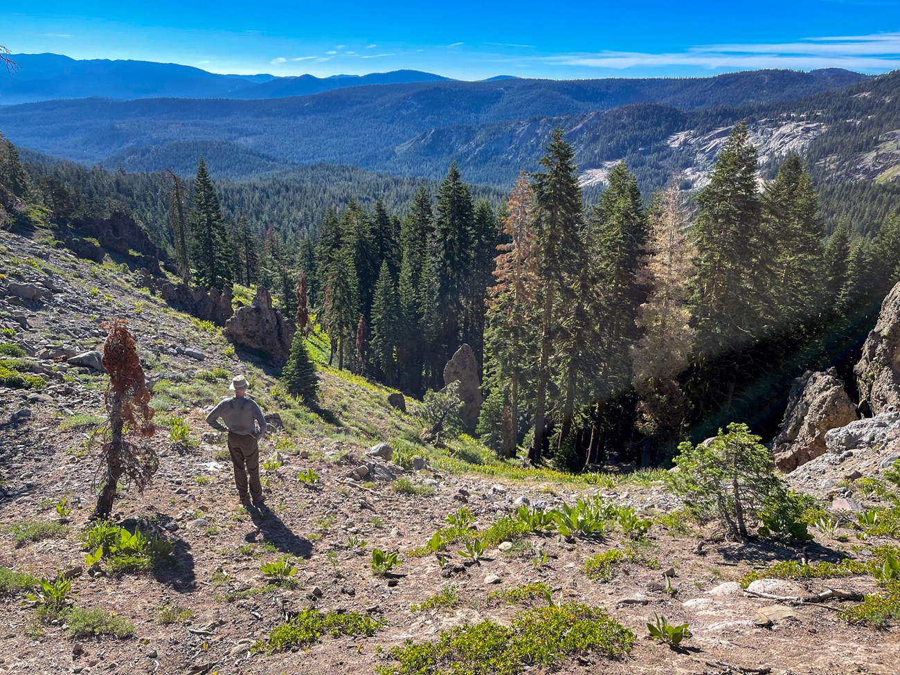 Person standing at the top of a summit near a depression in the earth