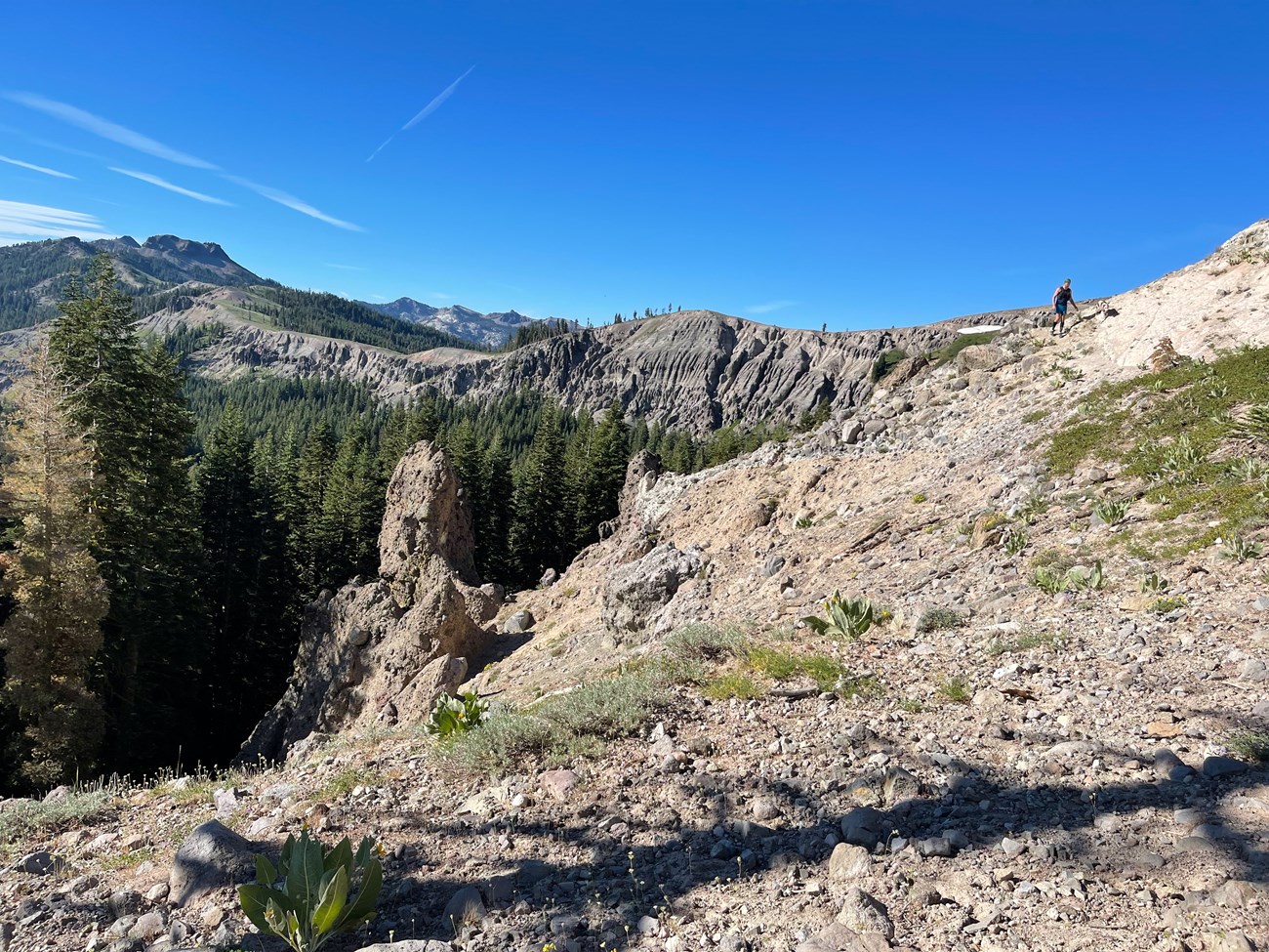 Rocky landing overlooking a steep decline. A hiker is seen in the distance