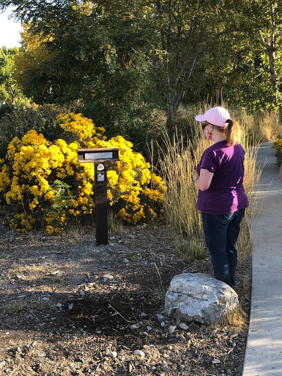 A woman stands next to a trail marker post.