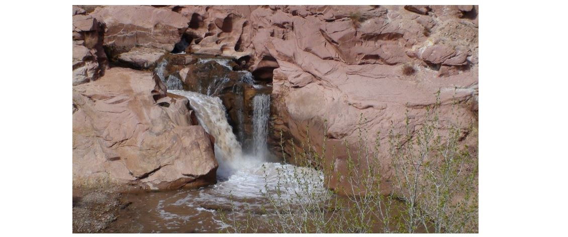 Photo shows a substantial drop in the river with two side-by-side waterfalls and a pool below. The entire setting is rocky.