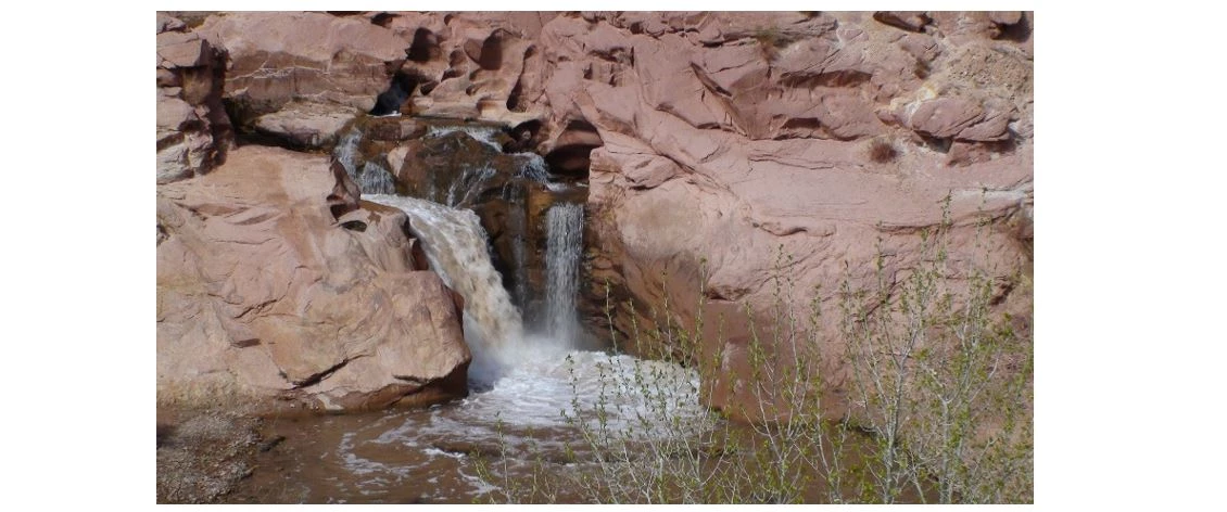 The waterfall barrier on the Fremont River prevents fish from moving upstream. Photo shows a substantial drop in the river with two side-by-side waterfalls and a pool below. The entire setting is rocky.