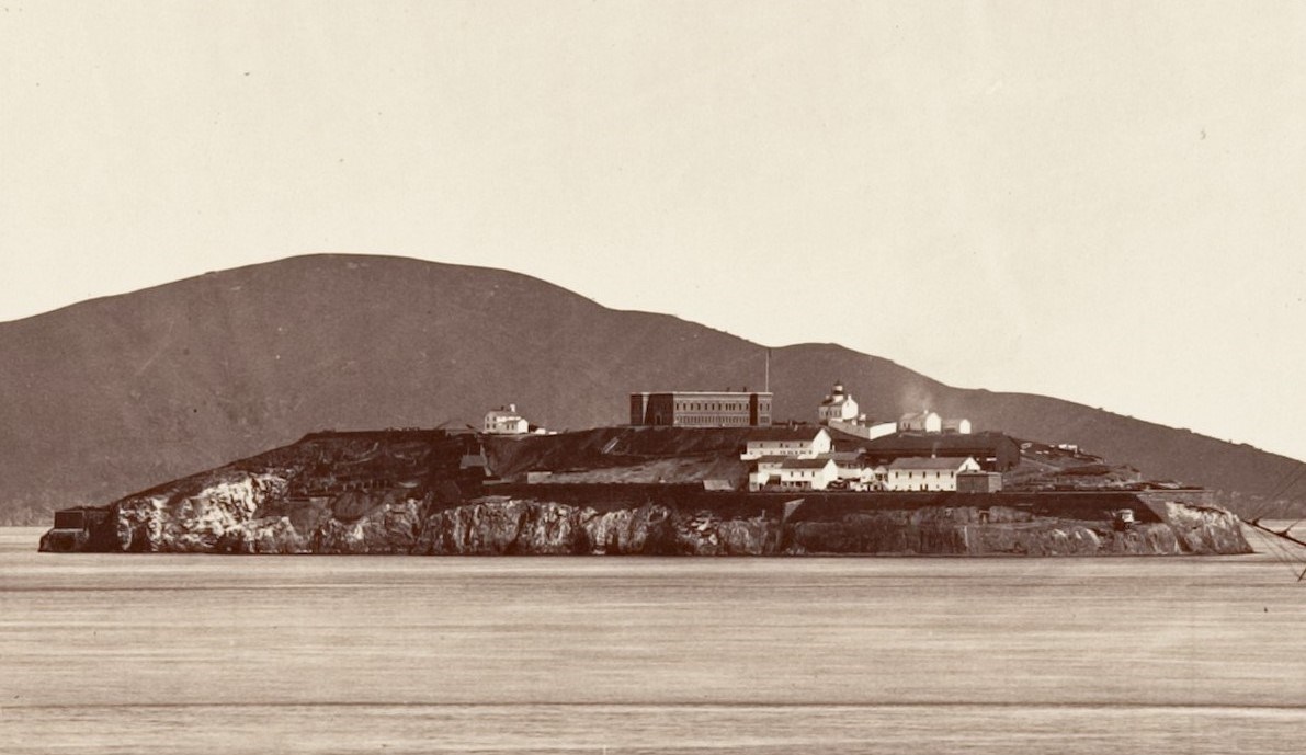 CAstatelibraryALCA 1867 Black and white photo of Alcatraz Island depicting a brick citadel at the top of the island and several other white buildings on the slope closest to the camera.