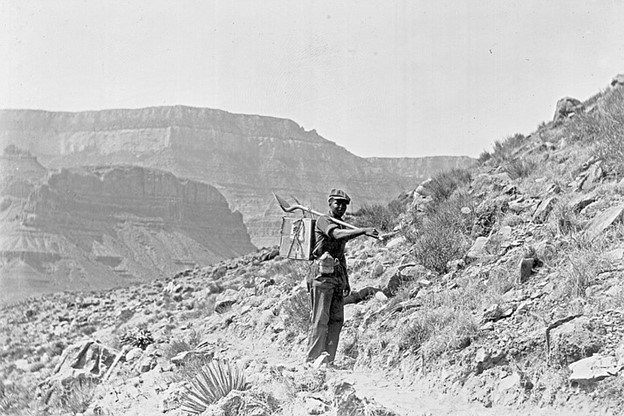 A black and white picture of a Black man stands on the trail at Grand Canyon