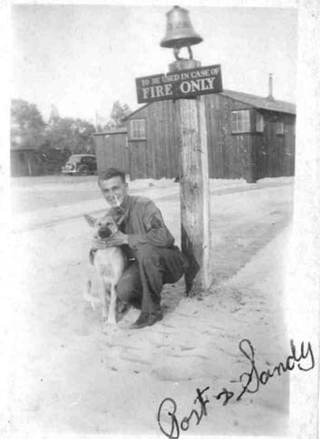 a young man in a ccc uniform squats next to a large dog