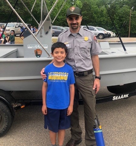 SECN Aquatic Ecologist Eric Starkey and his son, Benjamin. Man in uniform and boy in front of boat
