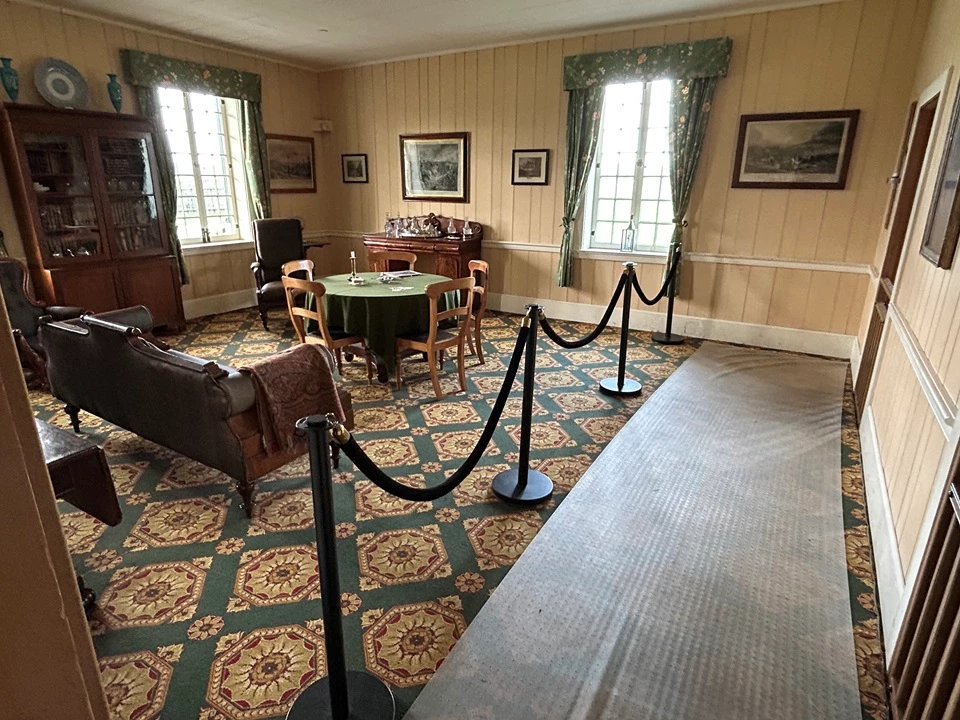CFH 2 The McLoughlin Sitting Room inside the Chief Factor's House. A Victorian-style parlor with polished wooden furniture, a sofa, a sideboard, table, and bookcase.