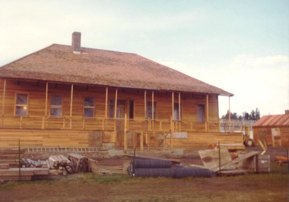 CFH D. Hansen 1976 crop 2 The Chief Factor's House under construction on a sunny day. The house is wooden and unpainted. Construction equipment and materials lie on the ground in front of the house.