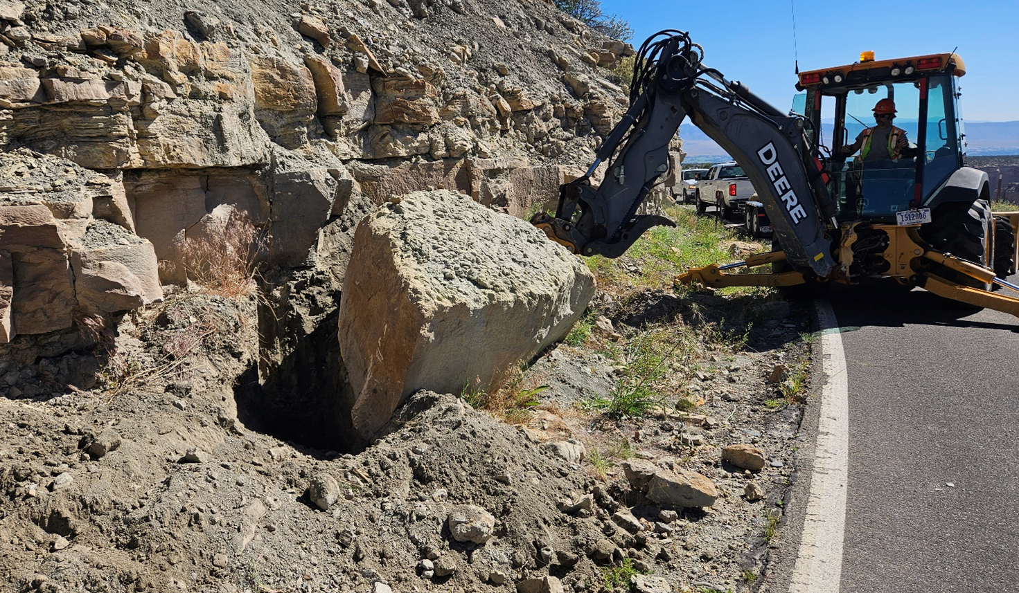 COLM Figure 2 Photo of a backhoe moving rocks along the side of a road.