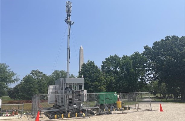 Temporary cell tower in a field with the Washington Monument in the background