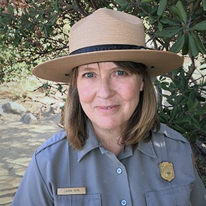 Kirn, a blonde woman in NPS uniform and flathat, smiles at camera