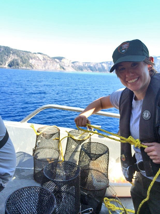 Crayfish traps Person on a boat, holding a rope attached to several black mesh crayfish traps.