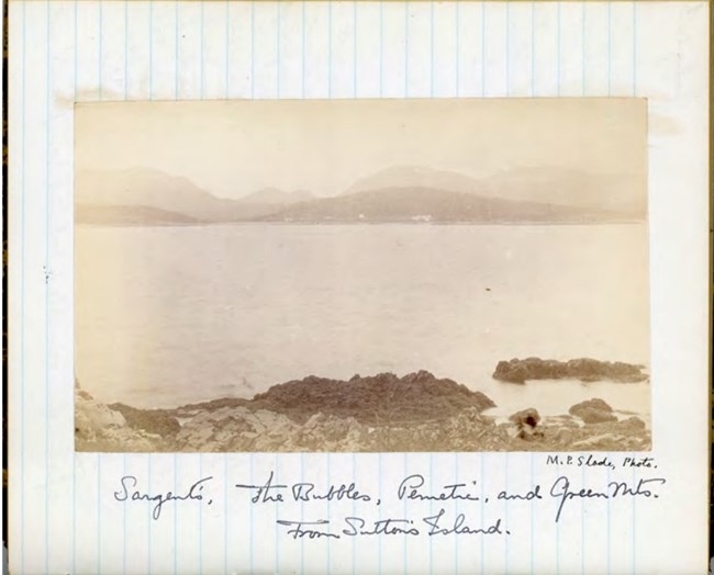 An old photograph looking across a bay at a small mountain range