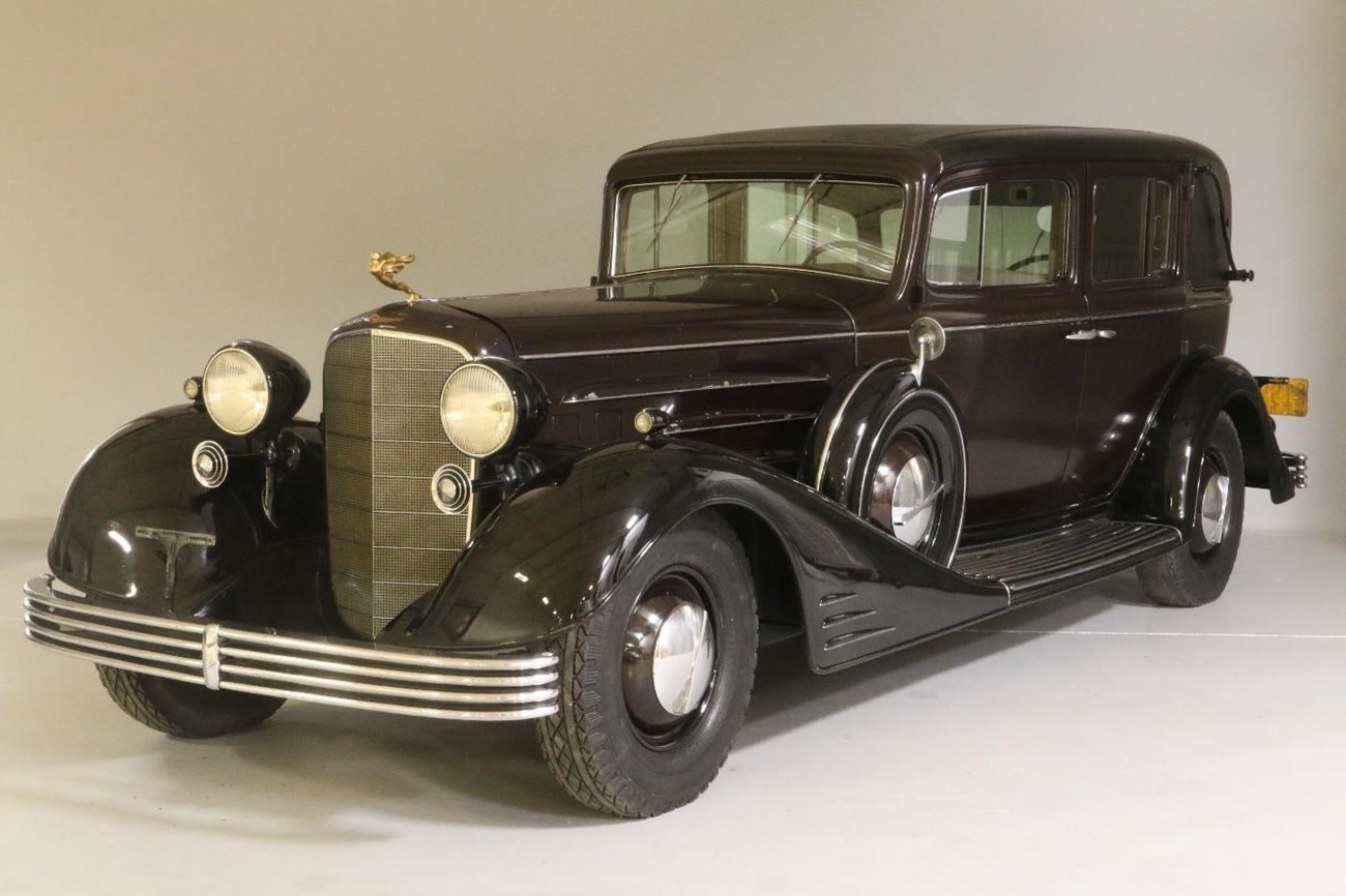 An automobile with gilt hood ornament.