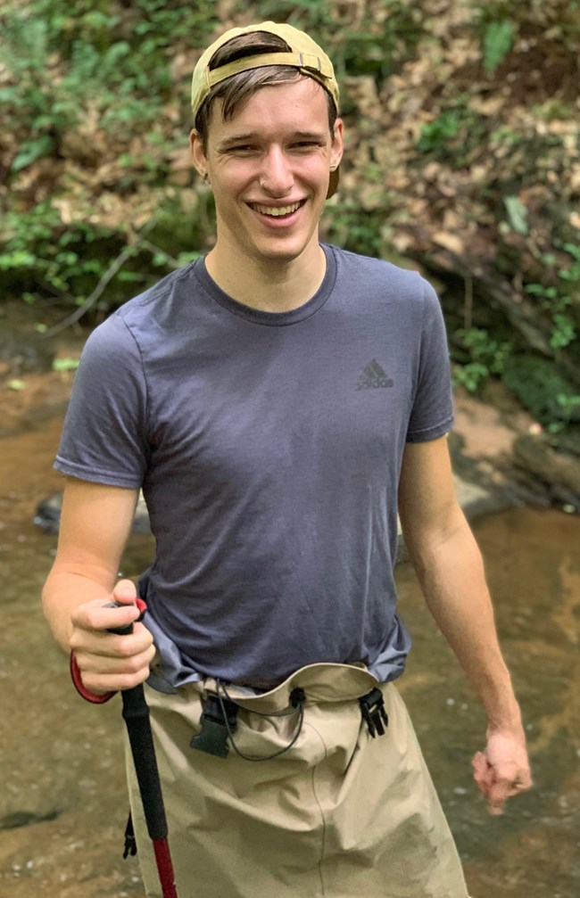 Caleb Sytsma Caleb standing in a stream, holding a stick