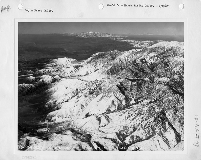 A historic aerial image of large, desert mountains.