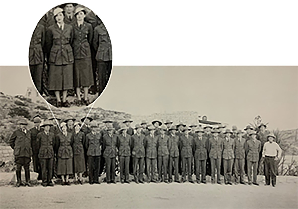 Two rows of uniformed NPS staff pose in front of a dusty mountain. A call out window shows two women wearing skirts and pith hats.