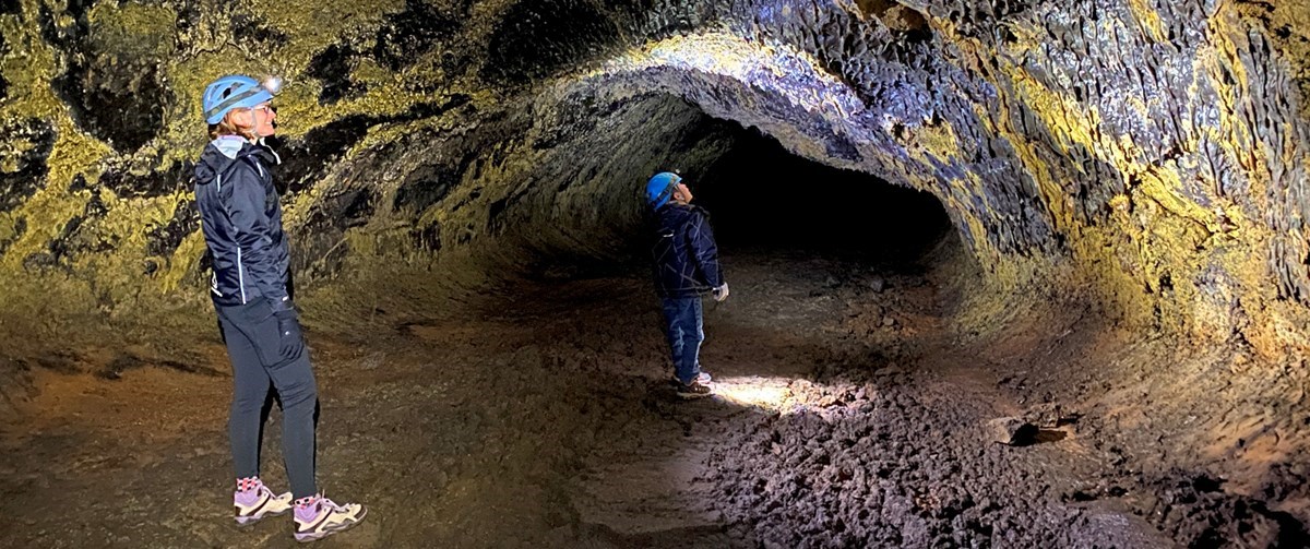 photo of 2 people standing in a lava tube