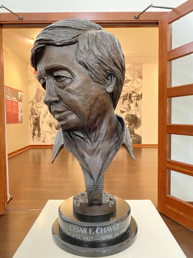 Bronze bust of Cesar Chavez sits on small table in monument visitor center.
