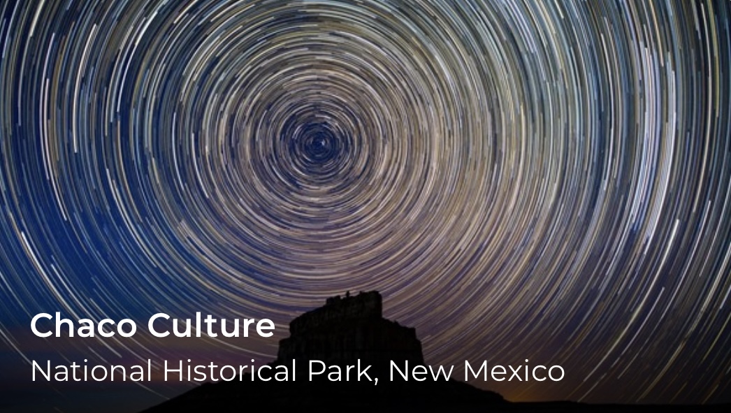 Star trails create a circular pattern and a silhouette of a rock