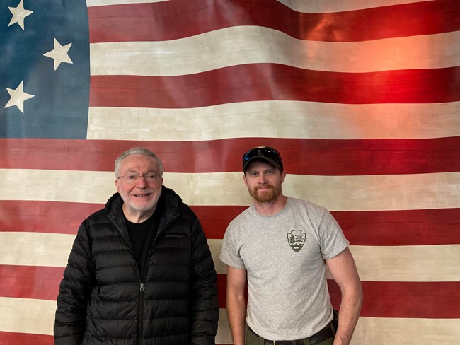 Volunteer Charles and Bud Conley in front of flag