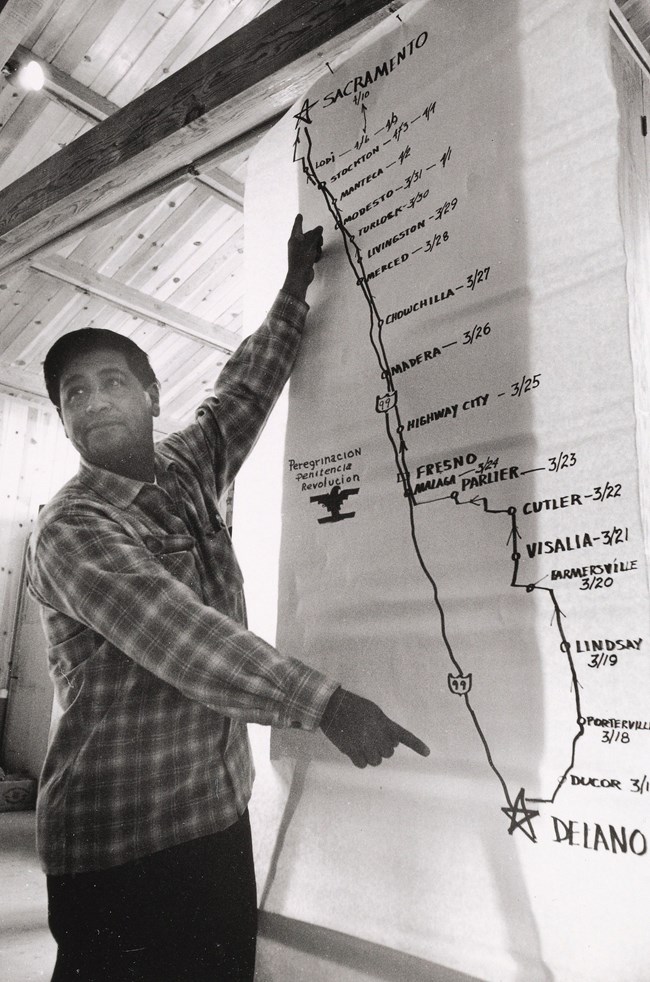 Cesar Chavez stands in front of a map of 1966 march route. Cesar Chavez stands in front of a map of 1966 march route.