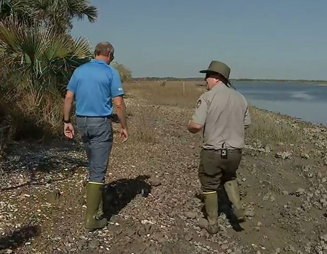 two men walking on shoreline of marsh