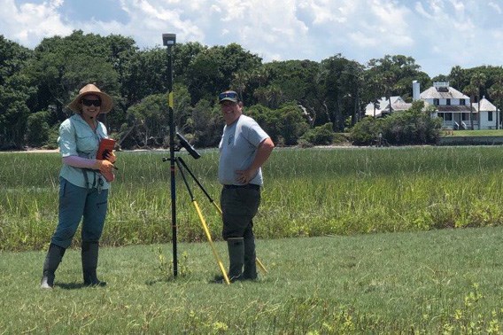 Abby Gonzalez and Ches Vervaeke at TIMU two people standing with a tripod in front of a marsh