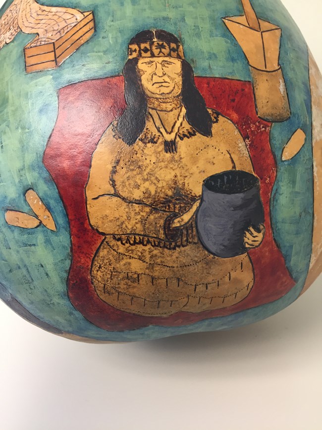 Pottery art showing a woman holding pottery with a corn pounder behind her.