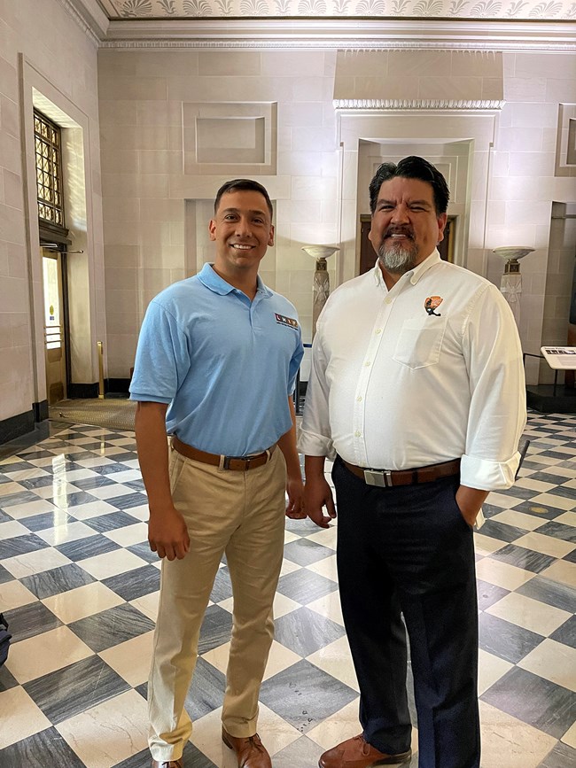 National Park Service Director Chuck Sams III and Esparza-Limón stand on a black and white tiled floor in a historic building.