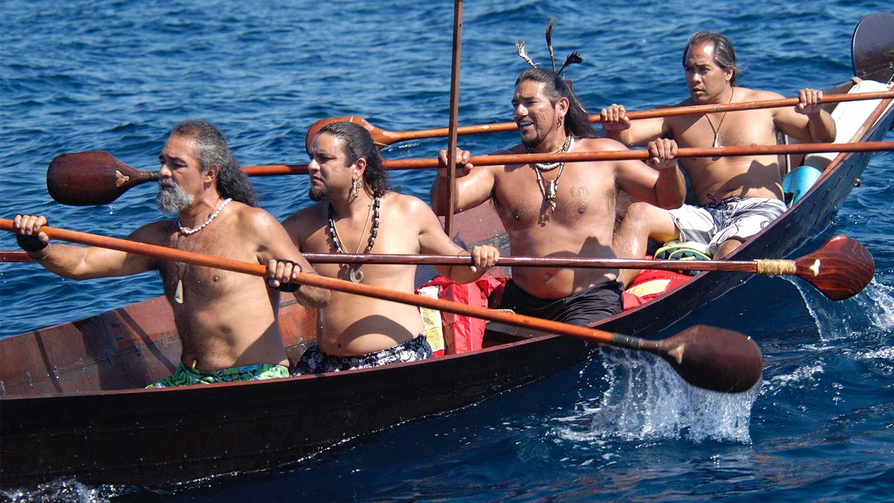 Chumash paddlers in tomol Four topless indigenous men paddle in wooden canoe
