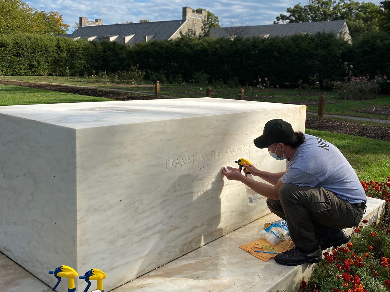 A man cleans a marble grave marker.