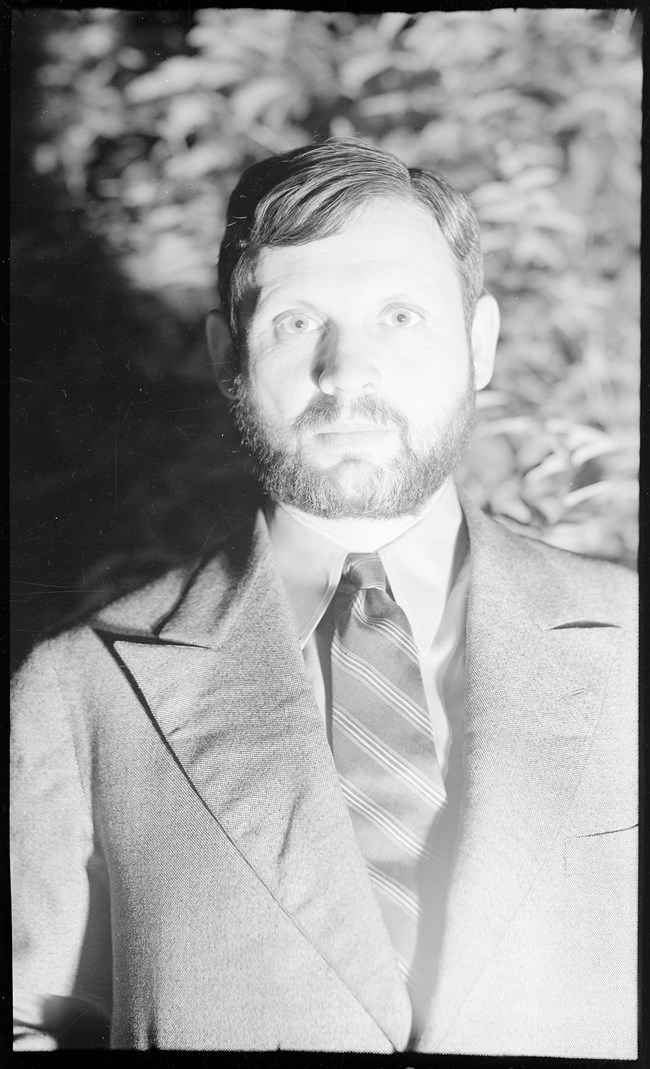 Portrait of a bearded man wearing a suit and tie.