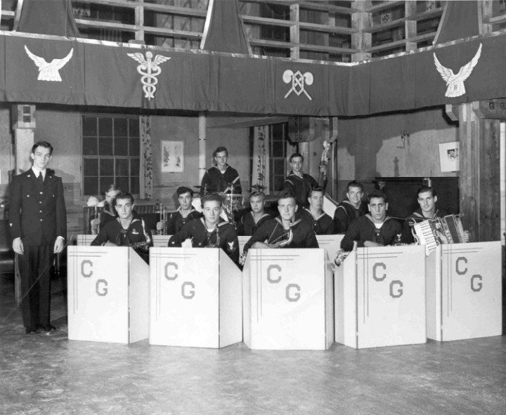 a group of young men in coast guard uniforms sit at podiums holding instruments