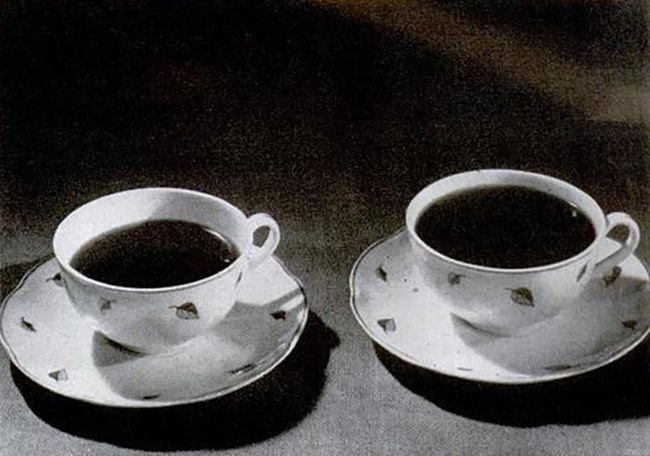 Two cups of coffee on saucers. The one on the right is full to the brim. The one on the left has less coffee in it.
