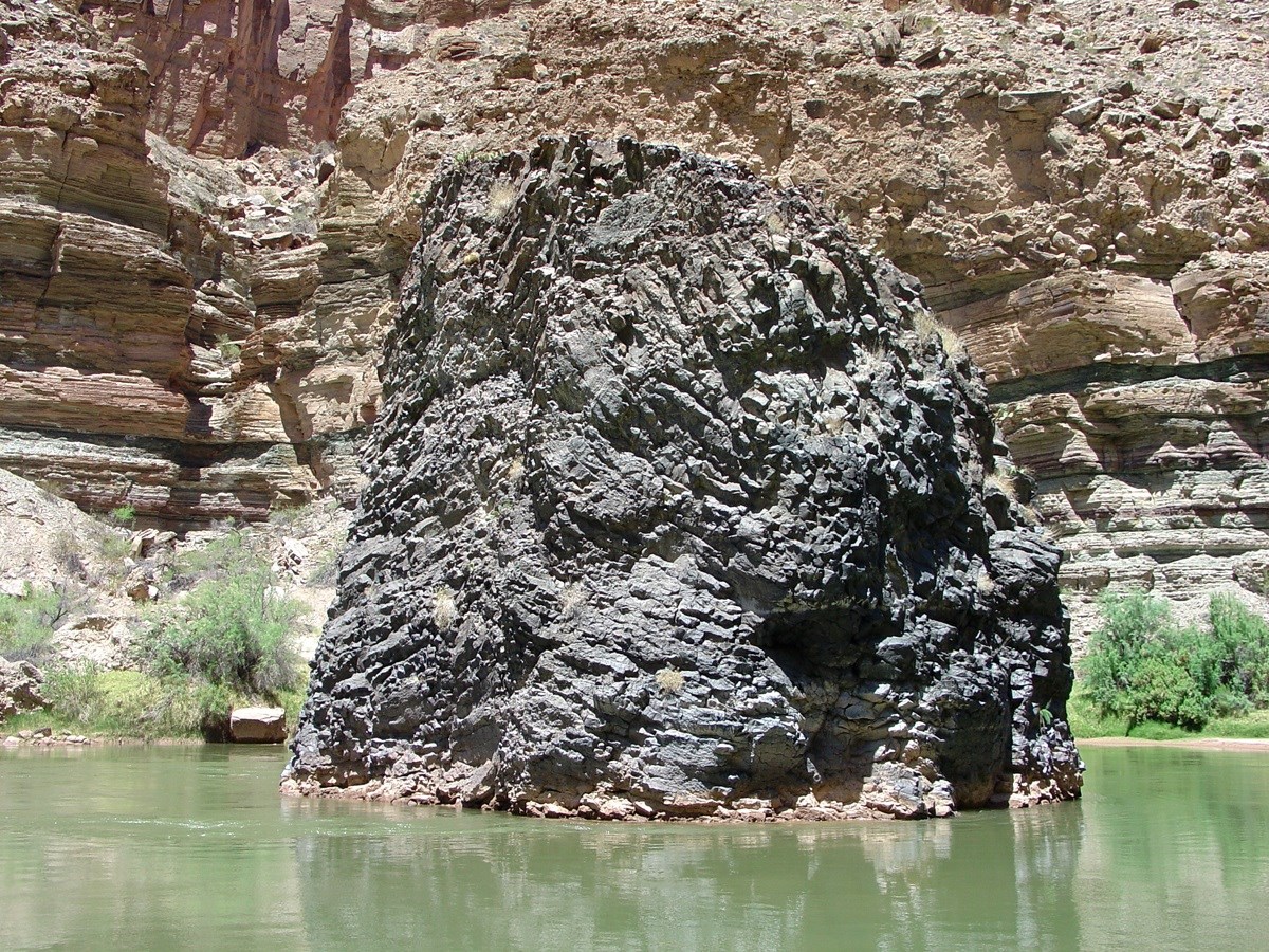 photo of a dark rock outcrop in a river