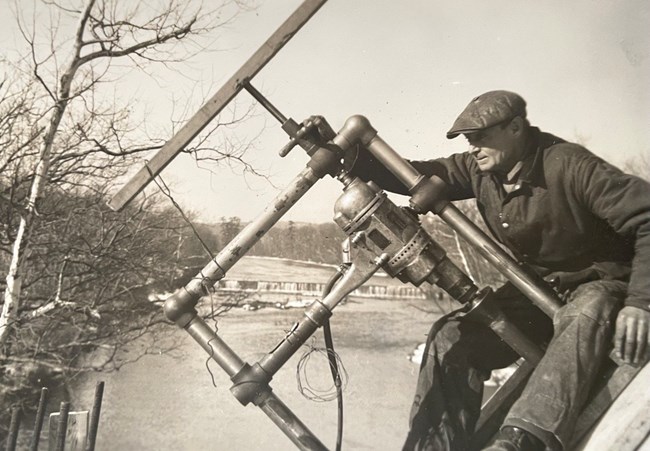 Man working a machine on a bridge with river in background