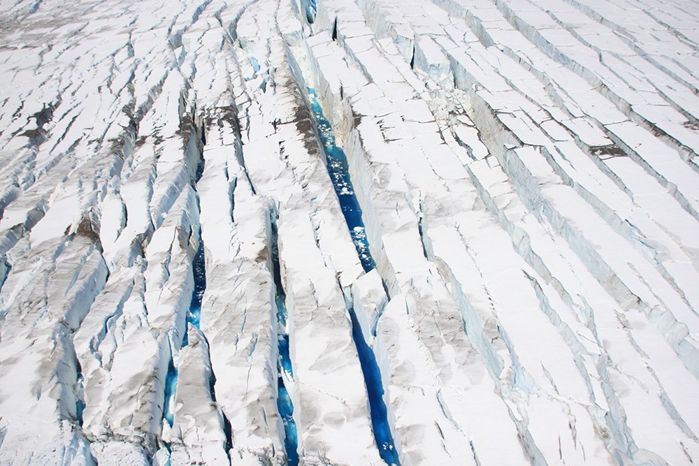 A close up view of glacier crevasses with pools of blue water.