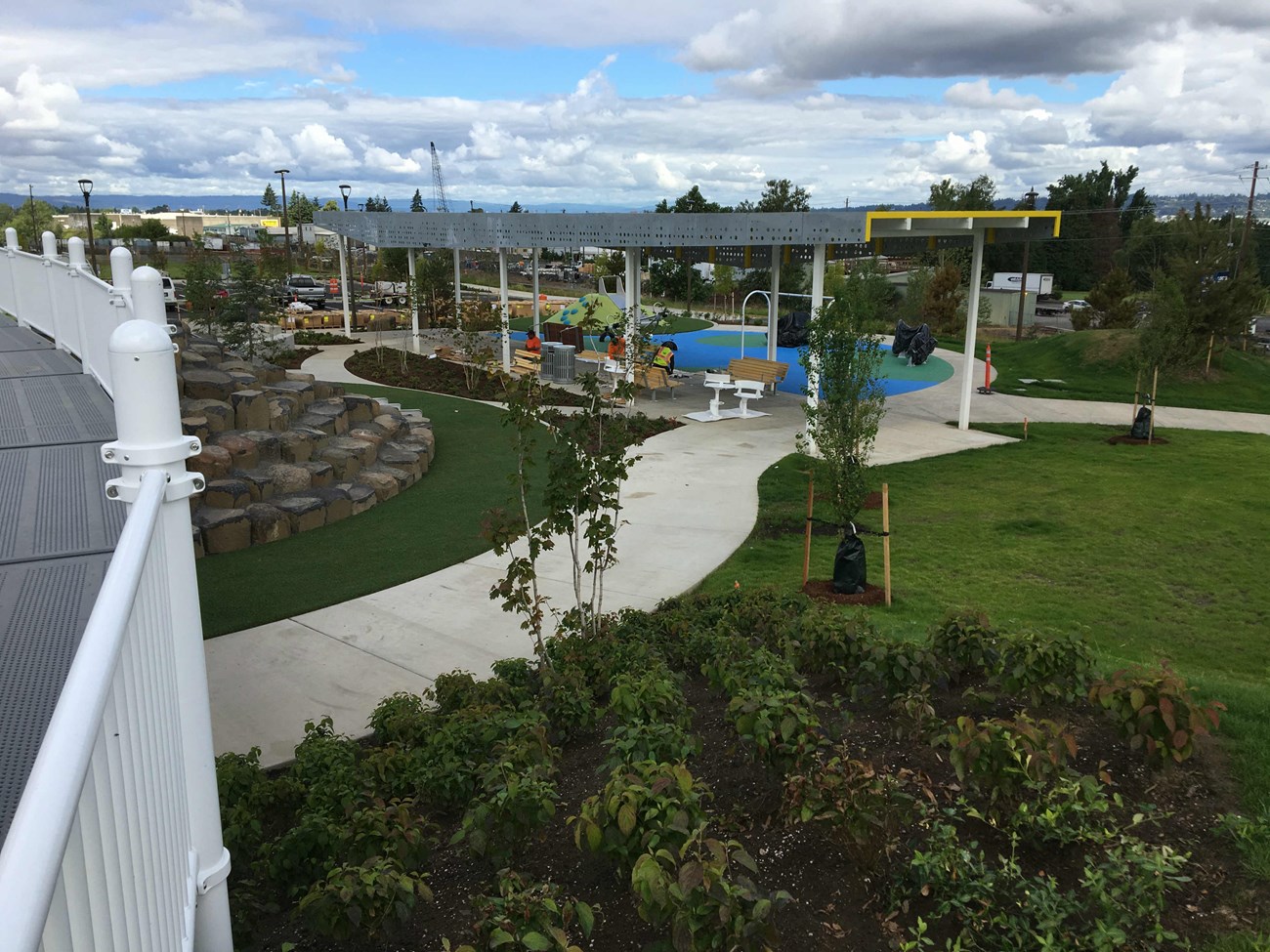 City park that includes a wide walkway leading to a large sheltered playground