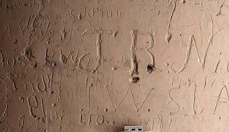 A raking-light photograph of historic inscriptions inside the Great House.