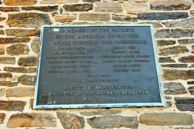 Bronze plaque with inscription attached to outside wall of masonry church