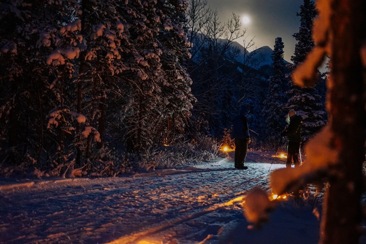 two people on a dark snowy trail in a forest