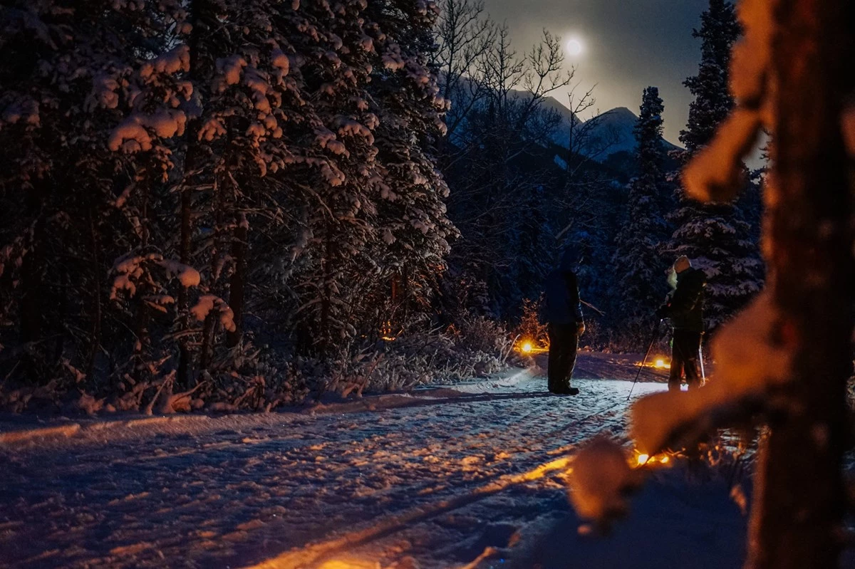 Winter solstice stroll two people on a dark snowy trail in a forest