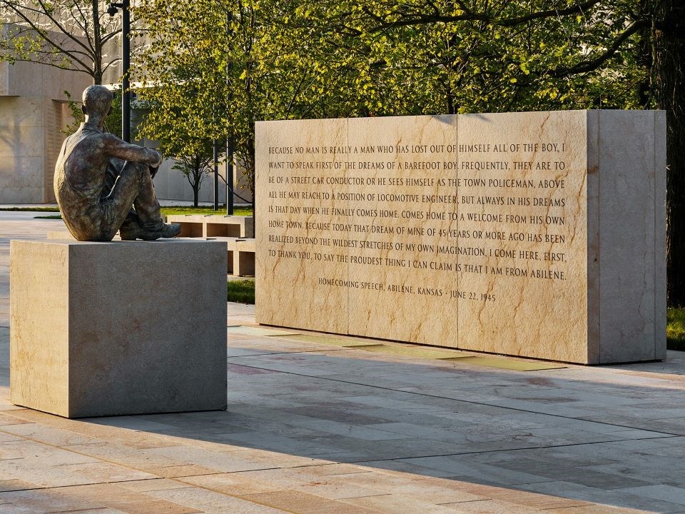 Statue of Dwight D. Eisenhower as a child sitting looking at a memorial wall with a long quote inscribed