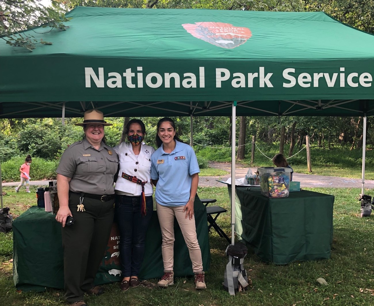 LCW Crop Three women stand beneath a National Park Service pop up tent