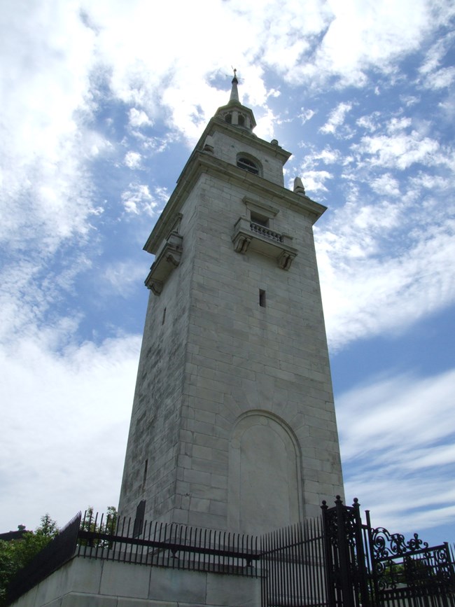 View from the foot of the Dorchester Heights Monument to the top with sparse clouds in the blue sky.