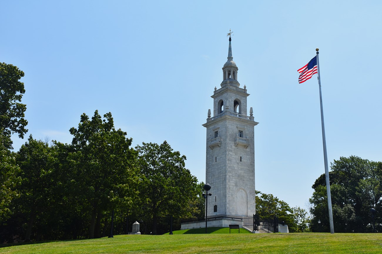 Dorchester Heights Monument with a flag pole to the right waving an American Flag.