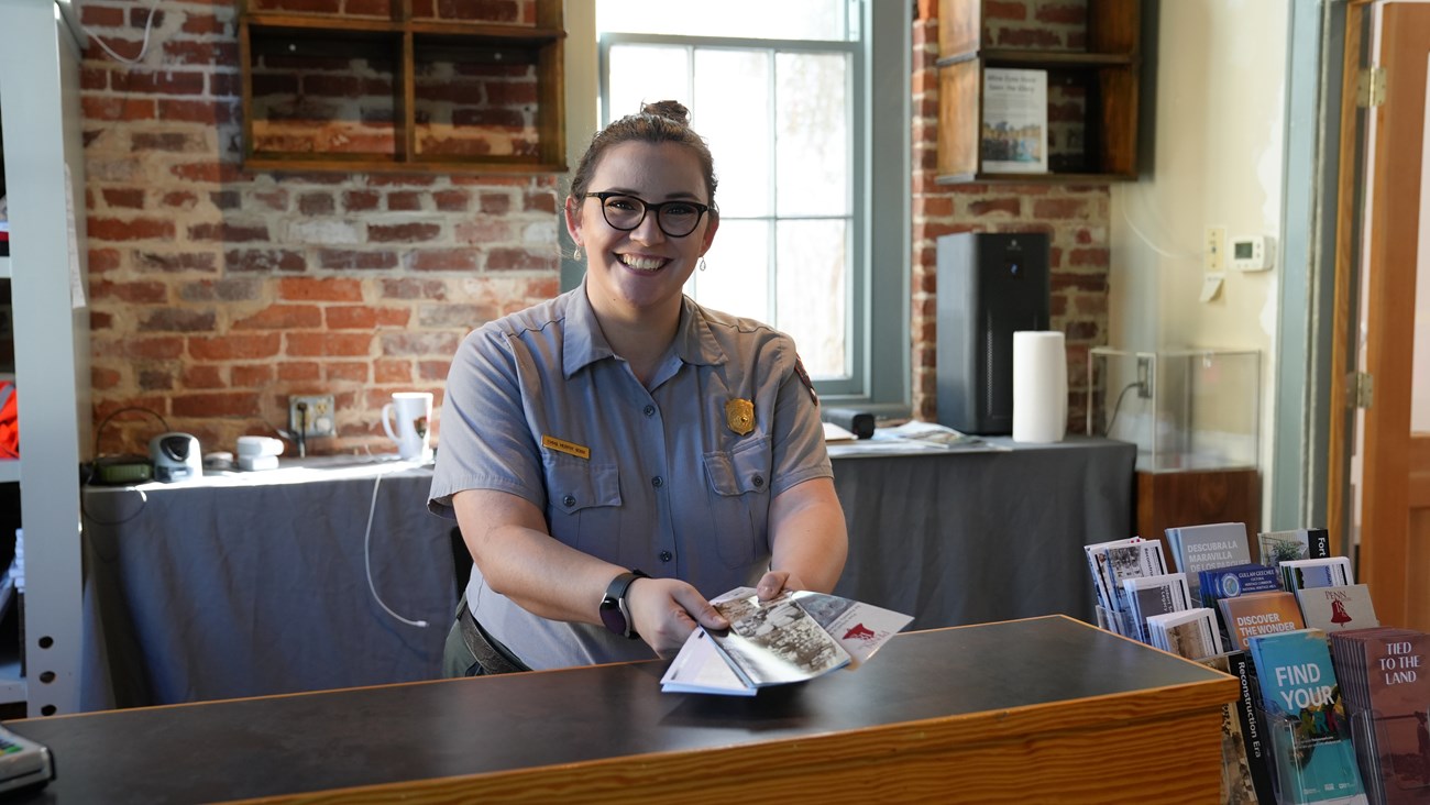 Ranger hands out brochures over a counter.