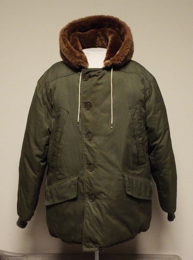 A front view of a heavy green parka with a brown fur hood